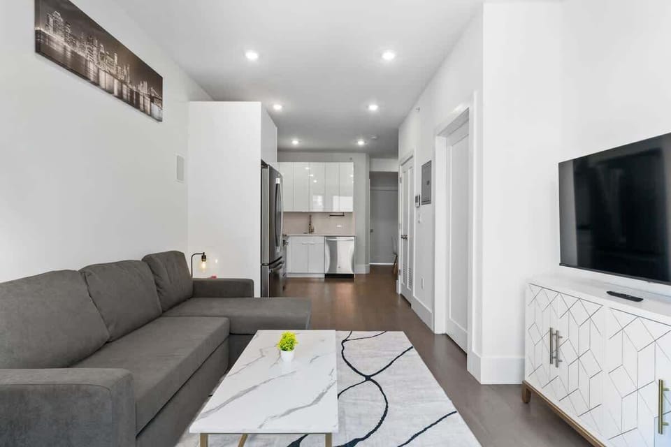 A wide view showing the living area leading into the crisp white kitchen. The layout is open, practical, and easy to move through.