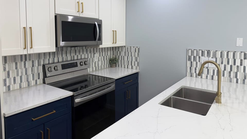 Step into your fully-equipped kitchen where culinary adventures await! With gleaming quartz countertops, modern appliances, and stylish navy cabinets, you'll love preparing meals in this beautifully designed space.