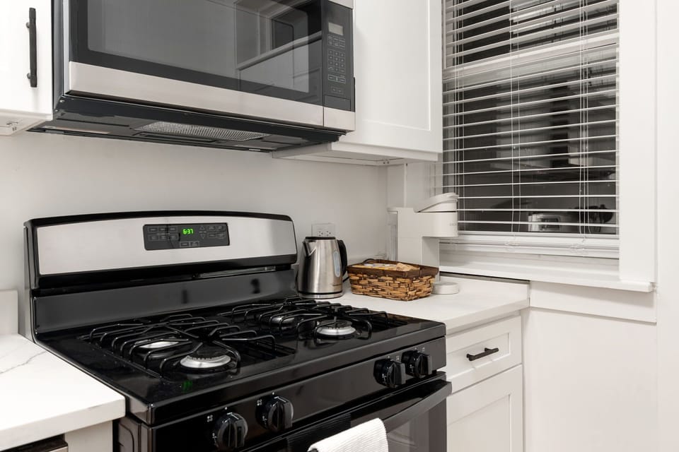 Clean cooking area w/ stove, hood & easy-to-reach essentials.