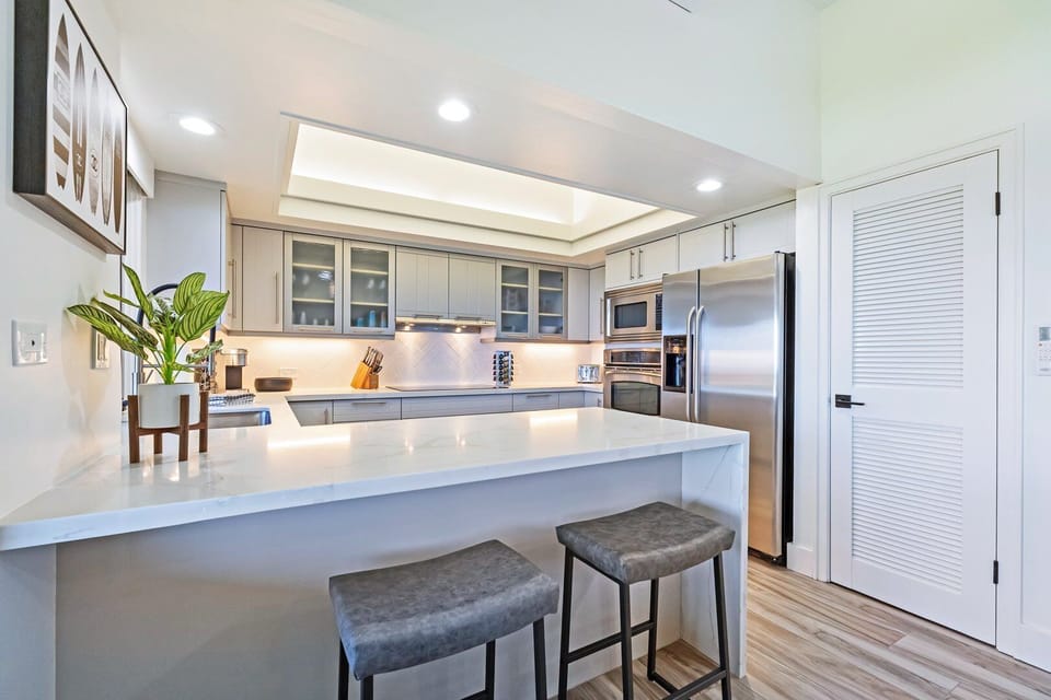Enjoy a modern kitchen with sleek white cabinetry, stainless steel appliances, and a large island perfect for casual dining.
