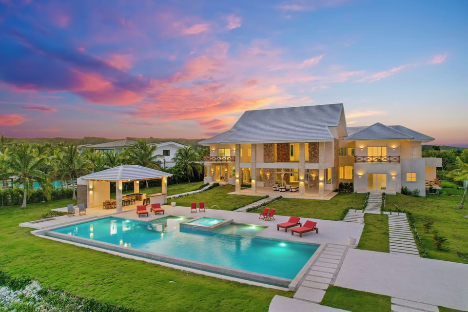 Toast the sunset as the villa and pool light up against a pink sky.