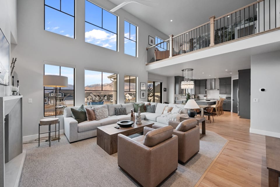 Expansive Windows with motorized blinds bring the beauty of the outdoors into the great room with plush furnishings a fireplace and smart TV