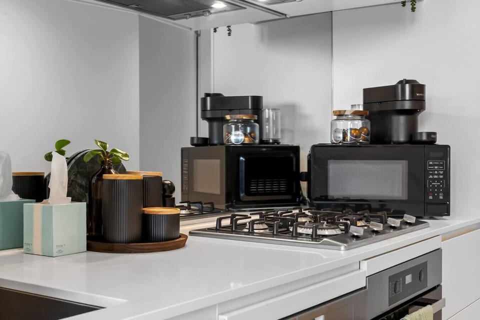Fully equipped kitchen with a gas stovetop, microwave, Nespresso machine, and drip coffee maker — everything you need to cook in or start the morning without leaving the apartment.