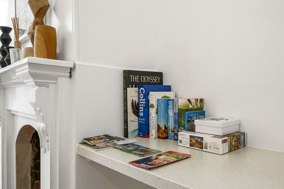 A cosy reading nook beside the fireplace, stocked with books, puzzles, and local guides. Thoughtful touches for quiet downtime, with the period mantel adding character to the corner.