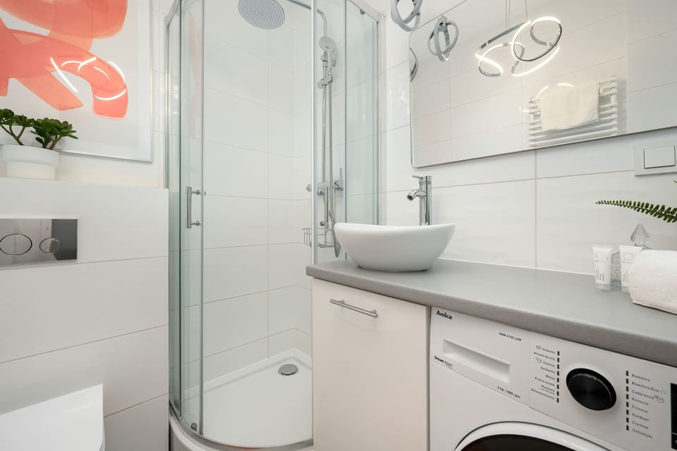 Bathroom with a washing machine, shower, and orange decorative accents.