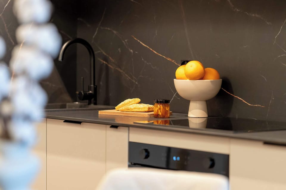 A modern kitchenette with a black worktop and functional space. 
