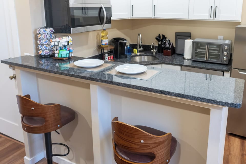 Modern kitchenette with sleek granite bar, cozy swivel stools, and a full coffee station, perfect for morning brews or casual dining.
