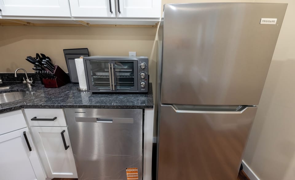 Modern kitchen with full-size stainless steel fridge, dishwasher, and oven toaster—ready for any meal!