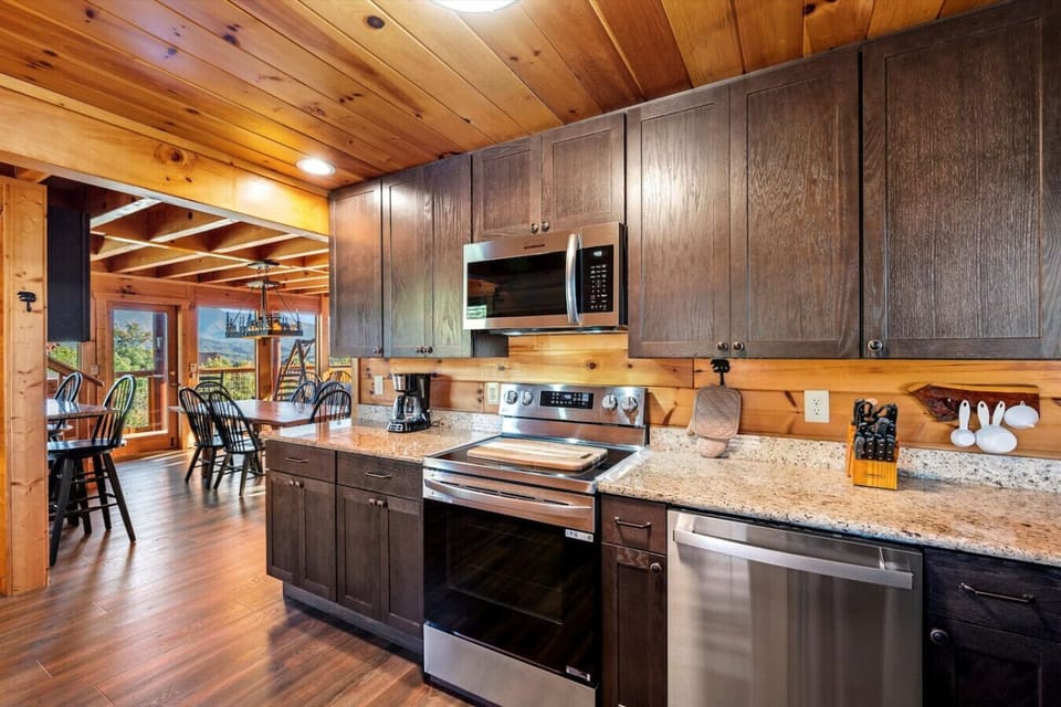 This fully stocked kitchen opens up to a warm dining space with mountain views just beyond the deck—perfect for family meals or a quiet morning coffee.