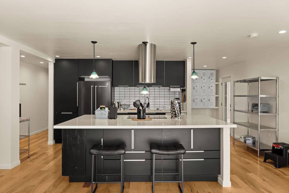 Step into a chef-inspired kitchen with sleek black cabinetry, gleaming countertops, and modern appliances ready for your culinary adventures.