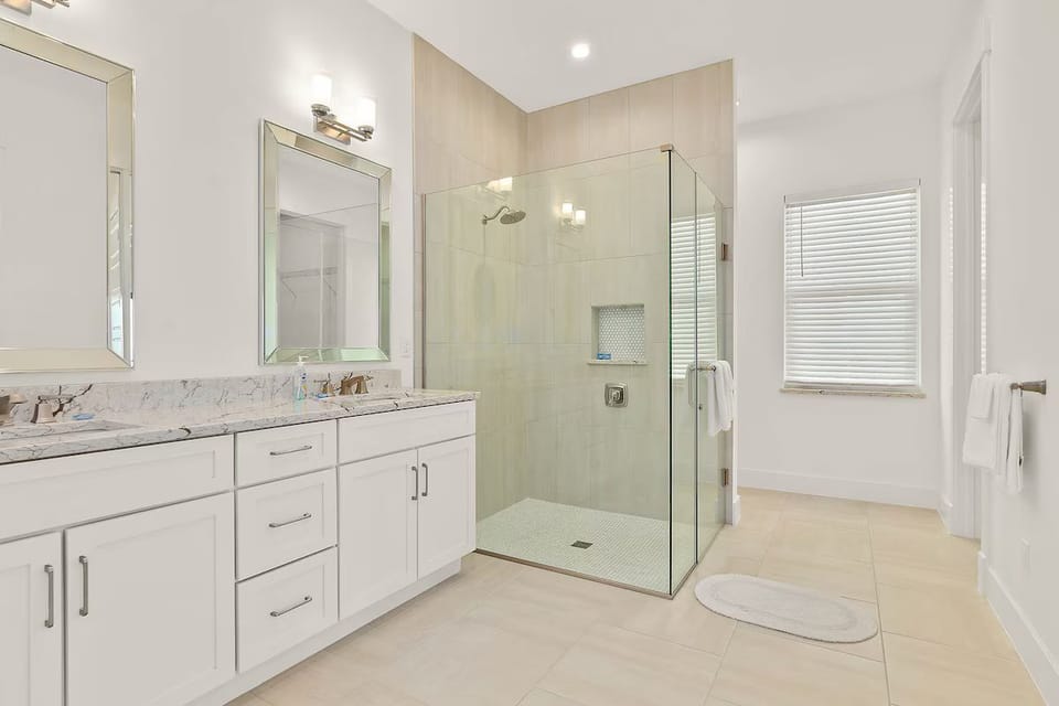 Bathroom featuring a white double vanity and a glass-enclosed walk-in shower.