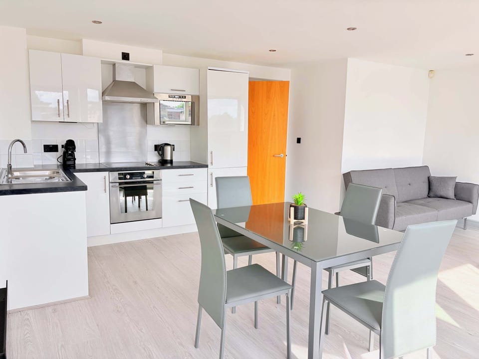 Modern open-plan living and dining area filled with natural light. Comfortable seating and a stylish table create the perfect space to relax, work, or enjoy meals during your stay in this York city-centre 2-bed apartment.