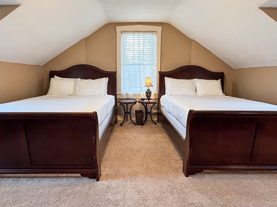 Upper level spacious bedroom with a two plush queen size beds with crisp white linens and second bathroom is on this level off the hall and has a step in shower at Aussie Cottage.
