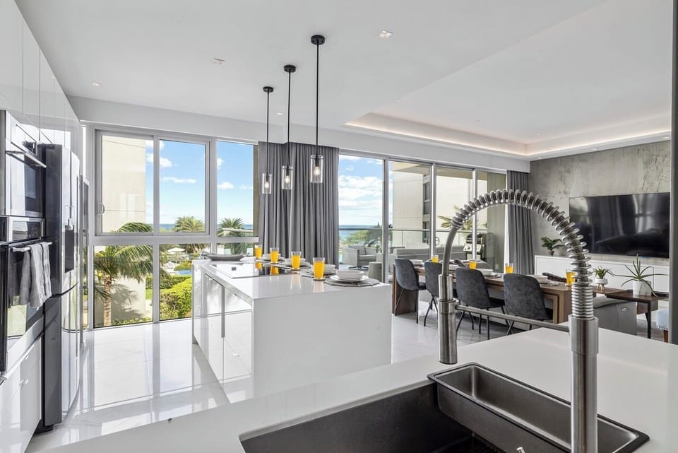 Your modern kitchen opens seamlessly to a sun-filled dining and living space, with sleek appliances and ocean views framing every meal you prepare.