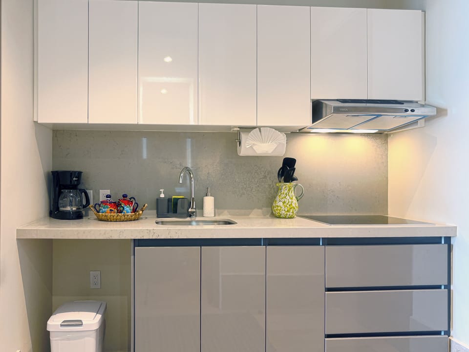 Fully Equipped Modern Kitchenette - The kitchenette at La Aurora offers everything needed for convenient in-studio meals, including a cooktop, coffee maker, sink, and ample storage. Clean lines and bright lighting make this compact space both functional and stylish for longer stays.