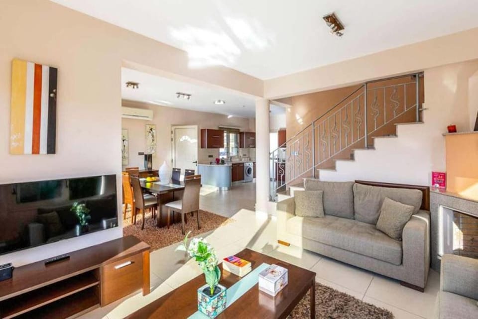 Open-plan living room with sofa, dining area, kitchen, A/C, WiFi internet, and satellite TV