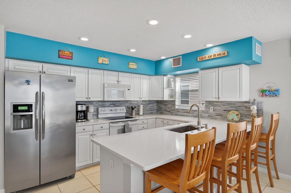 Open kitchen w/ island seating and dining table, perfect for shared meals.