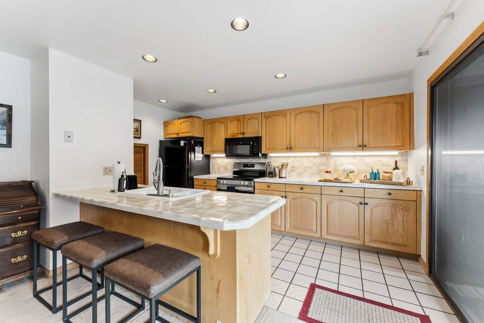 Kitchen: Drip coffee maker, Crockpot, blender, toaster, cooking utensils, tableware, bar seating for 3 at tiled island
