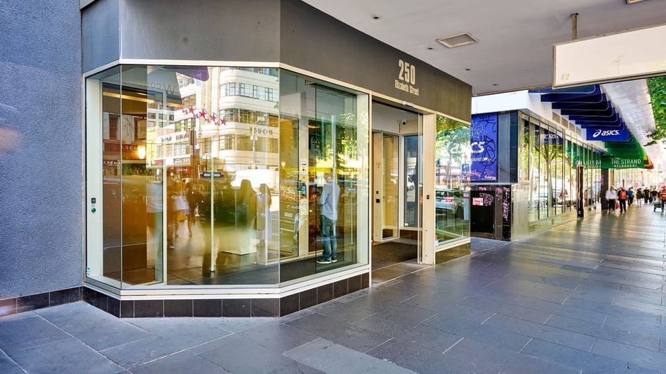 Street-level entrance with secure building access and nearby shops
