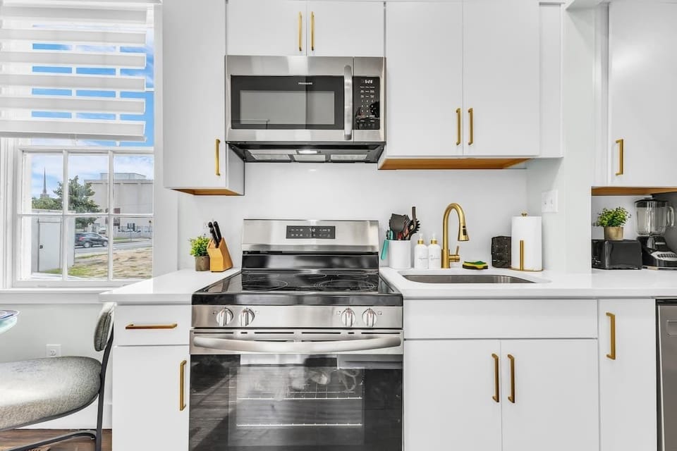MAIN FLOOR: Cook like home in this fully stocked, modern kitchen with stainless steel appliances, gold accents, and plenty of natural light. Perfect for family meals or cozy nights in during your getaway. #SavannahStay #AirbnbSavannah #VacationRenta