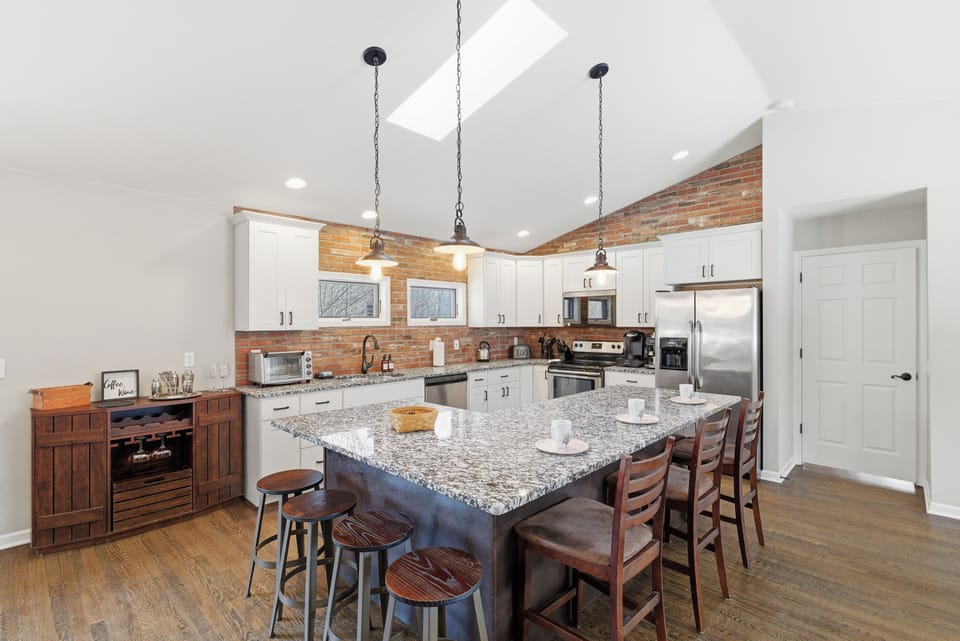 Spacious modern kitchen with granite island, skylight, and seating.