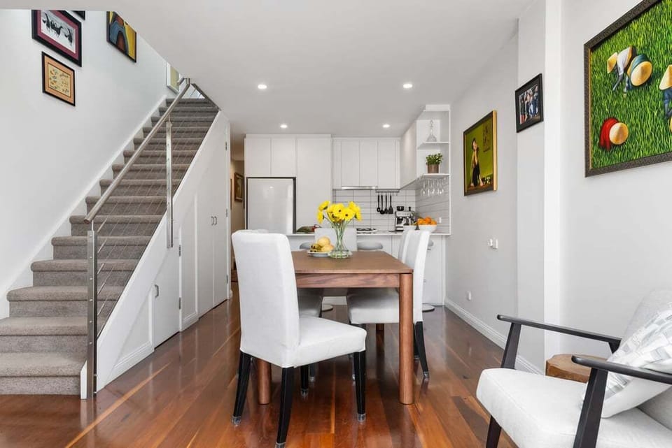 DINING: The dining room conveniently adjacent to the kitchen has a wooden table that comfortably seat six. It is surrounded by the owners artworks collected from around the world. The broom cupboard is under the stairs.