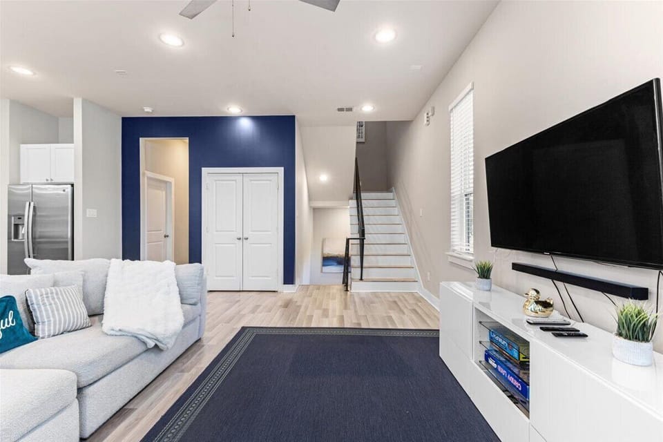 Bright and inviting living room with a plush sectional, 75" Smart TV, and bold accent wall. Perfect for relaxing or entertaining with family and friends.