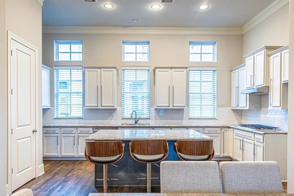 Ample natural light from large windows enhances the elegant and inviting atmosphere—ideal for cooking or socializing.
