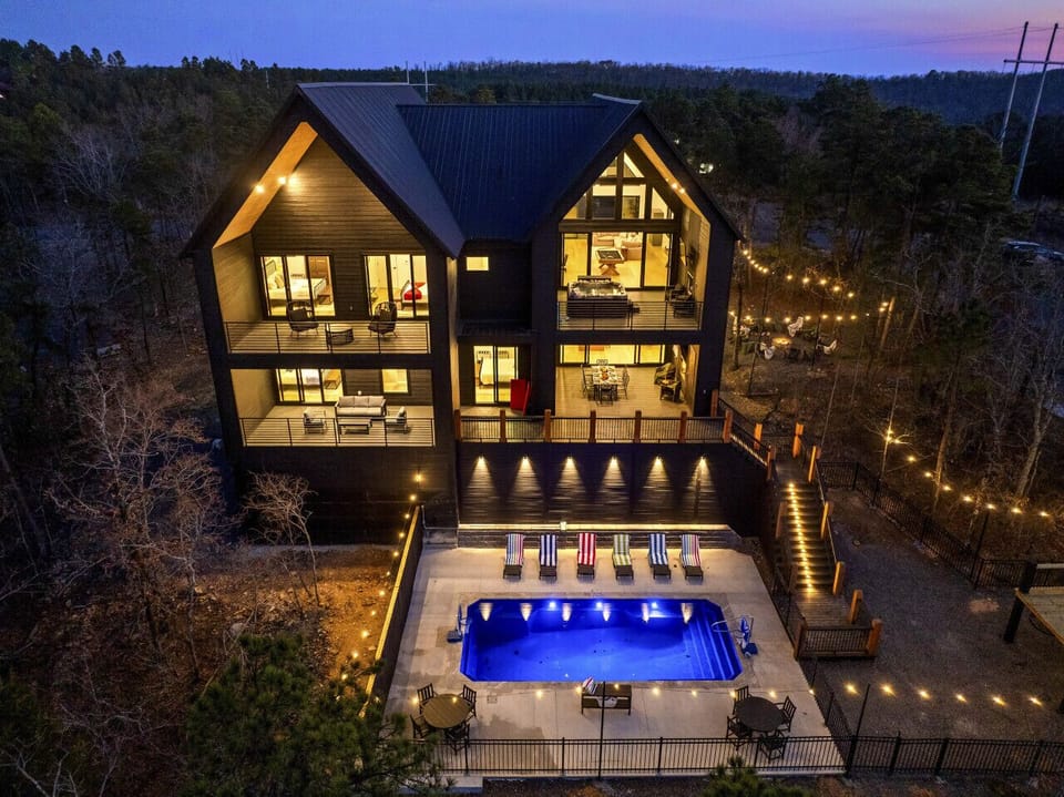 Floor-to-ceiling windows, two stories of open living space, and a glowing pool right outside — this place makes a first impression.