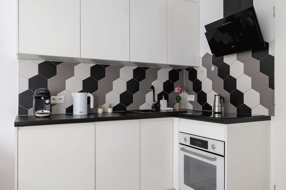 Bright white kitchen equipped with generous storage, expressive geometric backsplash and a compact dining table perfect for everyday meals.