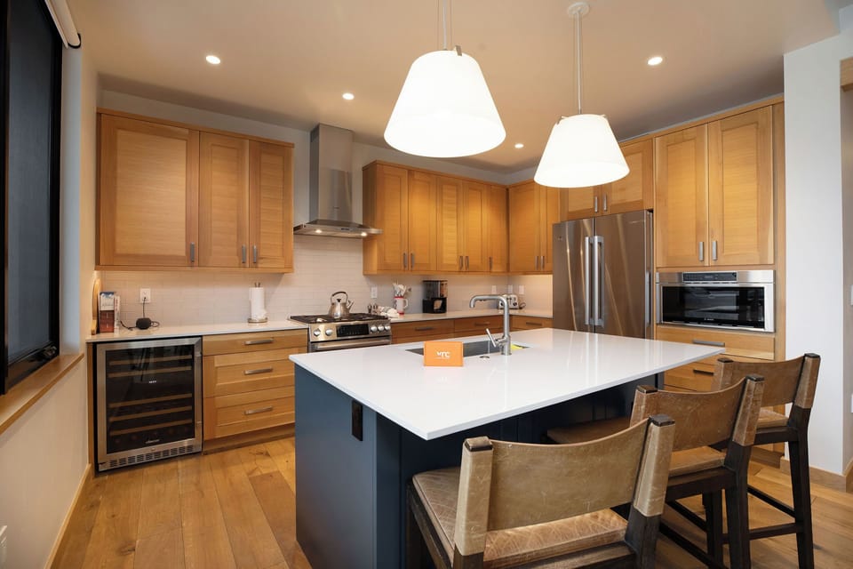 Spacious dining table seats eight comfortably with a gourmet kitchen and mountain backdrop