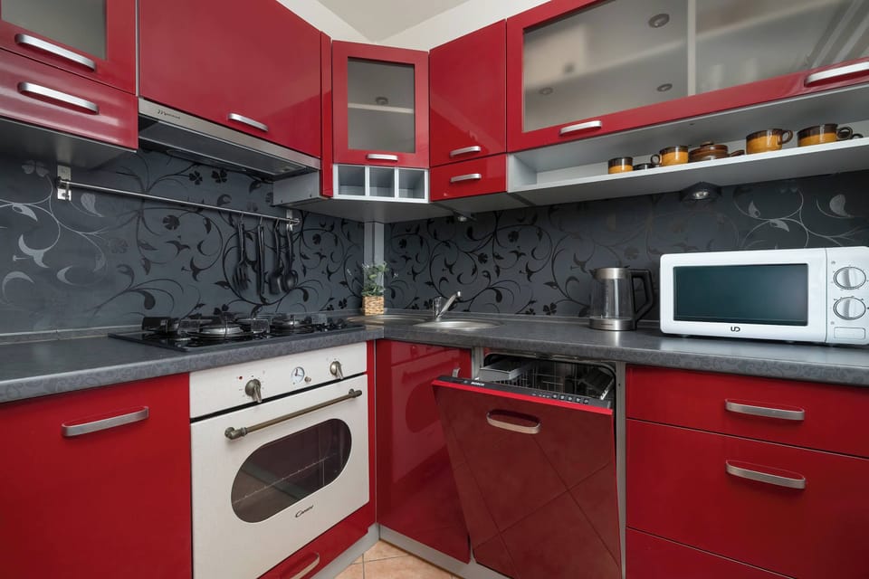 Compact red kitchen area with oven and stovetop.