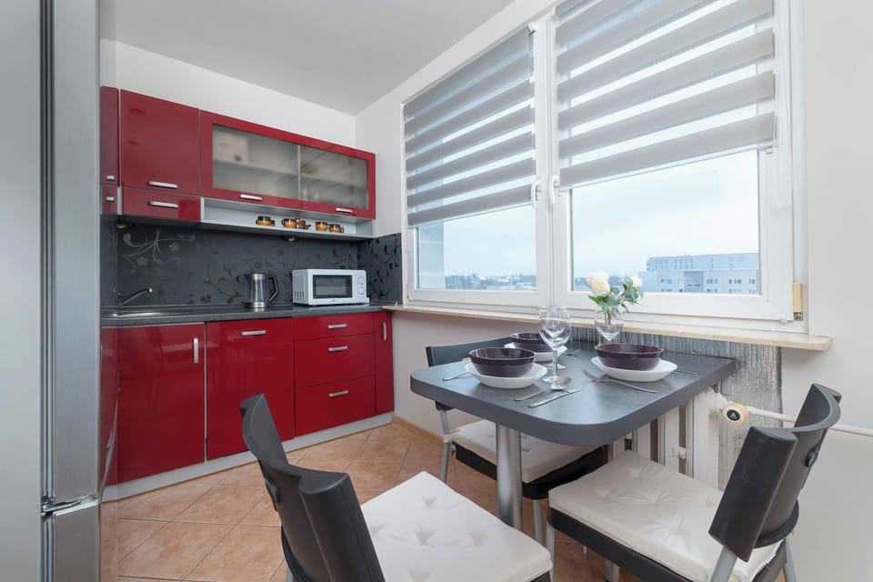 Red kitchen with dining space and large windows.