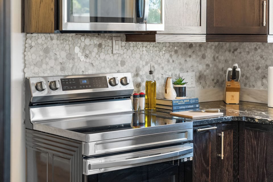 Sleek stainless-steel range + marble backsplash cook like a pro.