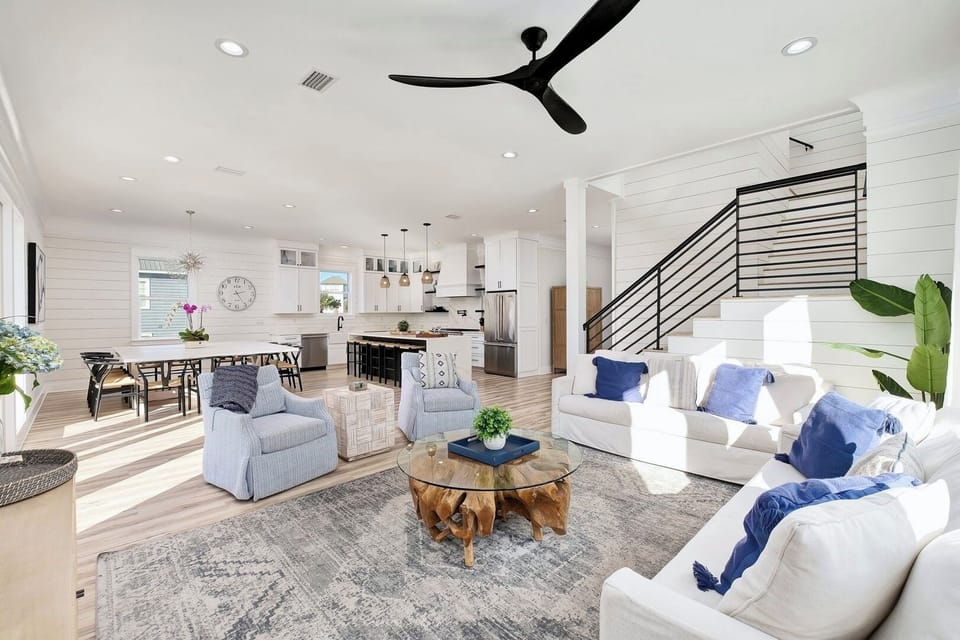 2nd Floor - Spacious coastal living room with designer furnishings, 4K Smart TV, and balcony access. Perfect for family gatherings, relaxing after the beach, and enjoying open-concept luxury steps from the Gulf.