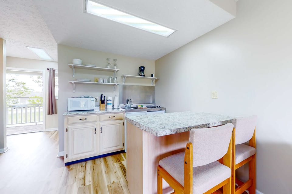 Eat-in kitchenette with granite breakfast bar, microwave, cooktop, coffee maker, dishes & cookware. Ideal space for long stays, weekend getaways, and budget-friendly travel with easy meals.