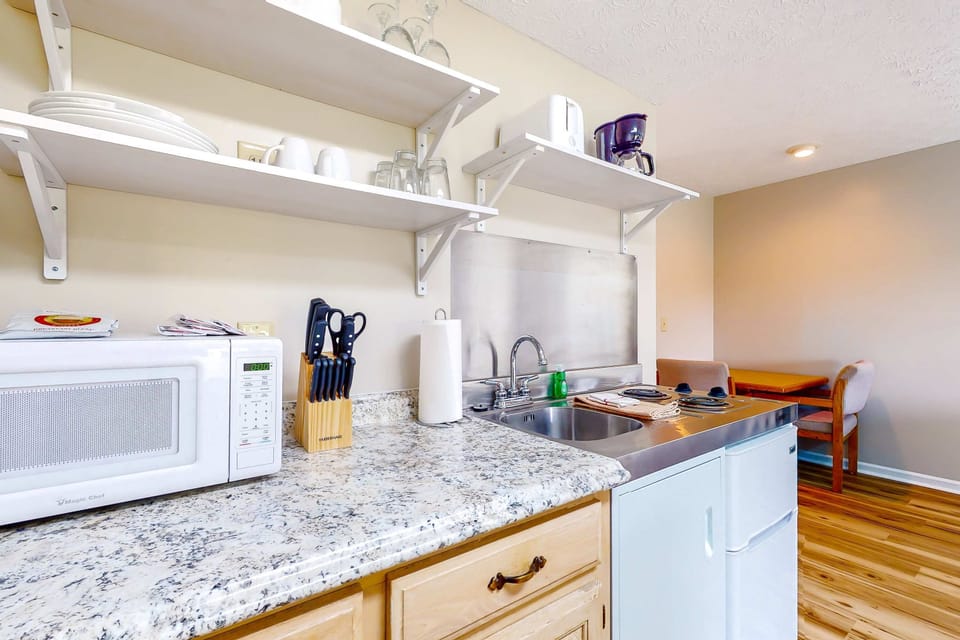 Fully stocked kitchenette with microwave, mini-fridge, cooktop, coffee maker, sink, dishes & glassware. Easy meal prep for extended stays, work trips, weekenders, and budget-friendly lodging.