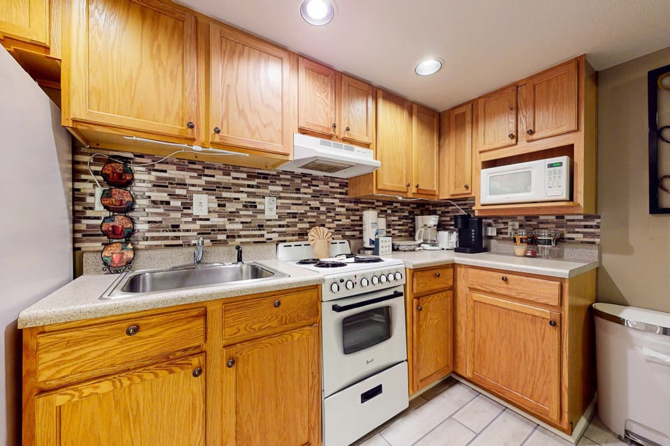 Fully equipped kitchen with stove, microwave, fridge & tiled backsplash. Cook, meal prep, and enjoy a convenient stay; great for families, long-term stays, and business travel with essentials, cookware, and coffee.