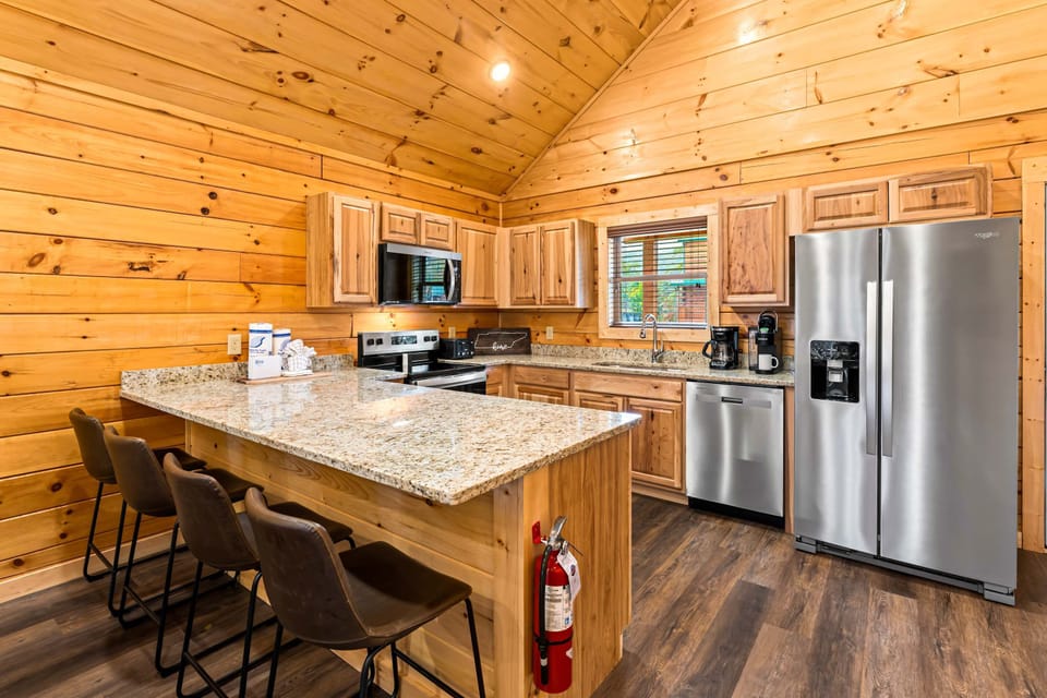 Open-concept kitchen with large island and bar seating. Great for hosting, cooking together, and making memories on your mountain cabin vacation.