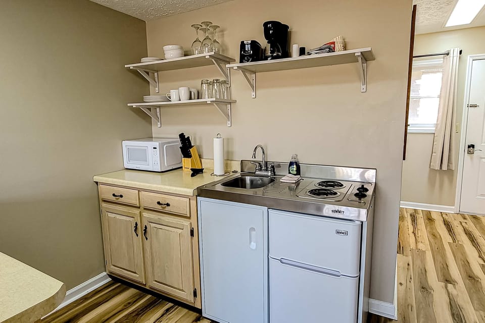 Convenient kitchenette with sink, microwave, mini-fridge, coffee maker & 2-burner cooktop. Stocked extended-stay, self-catering, budget-friendly, long-term essentials.