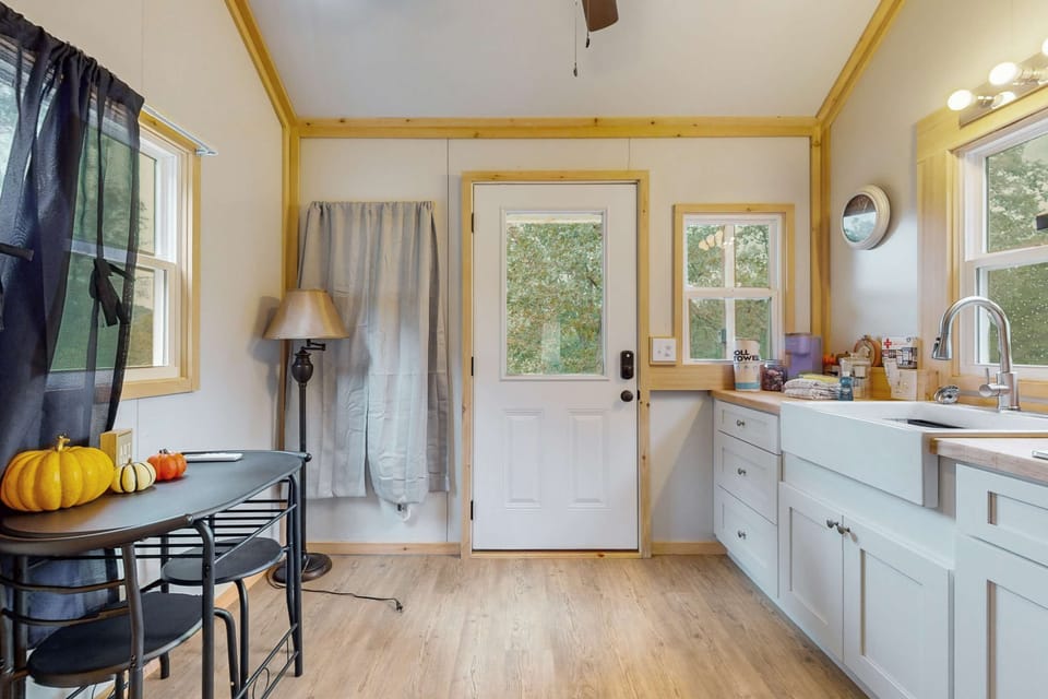 Open-concept tiny house kitchen & entry with lots of light. A farmhouse sink, ample counter space, modern-rustic design.