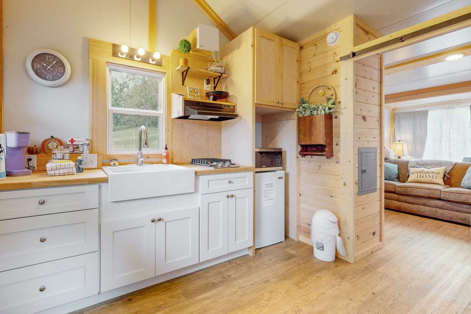 Bright kitchenette with farmhouse sink, gas cooktop, microwave & mini fridge. Fully equipped to cook meals with ease. Perfect for weekend escapes and longer stays.