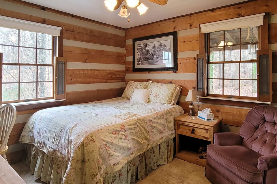 Your charming bedroom retreat awaits. A rustic charm meets nature views in this serene escape featuring warm wood accents!