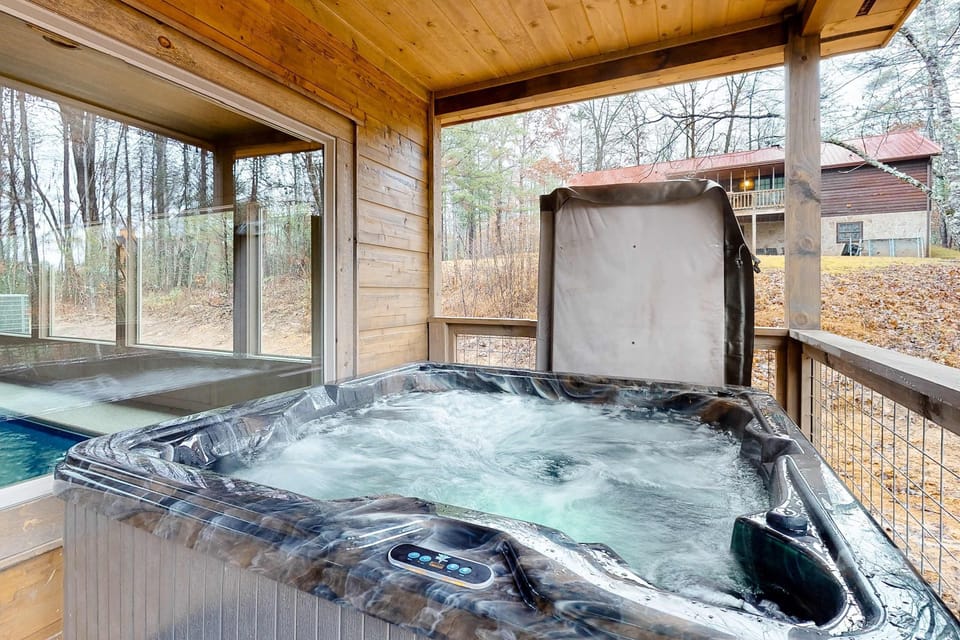 Private covered deck featuring a relaxing hot tub surrounded by the forest. A top-rated Smoky Mountains cabin amenity for couples, families, and group getaways.