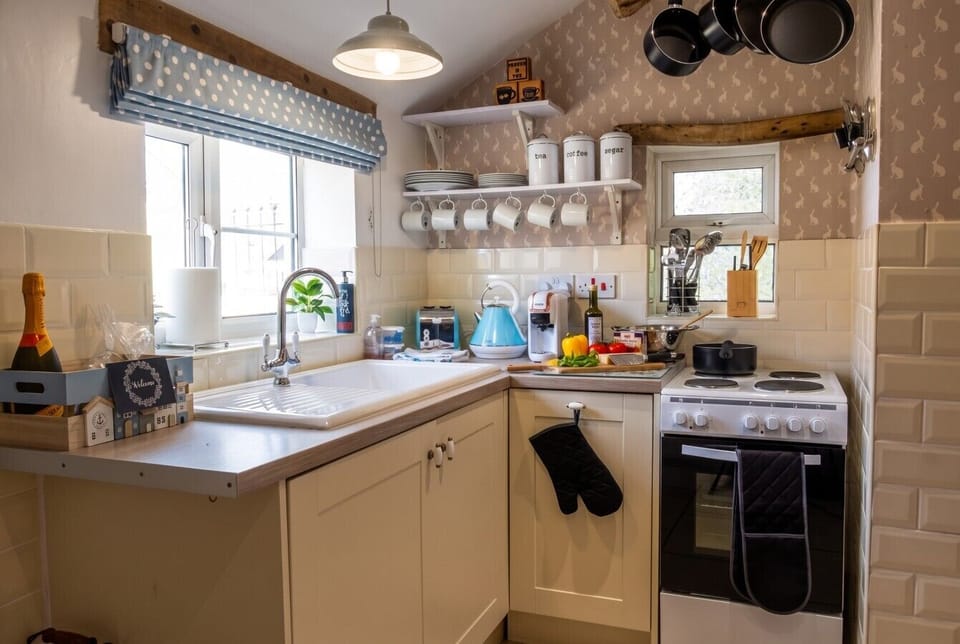 Kitchen with electric cooker, blue kettle, and welcome extras.
