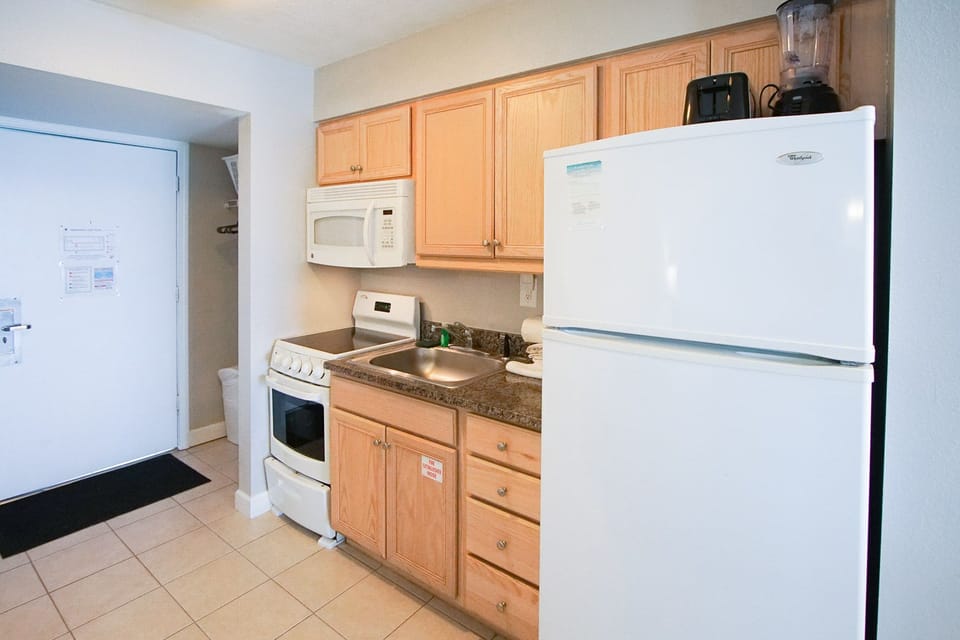 The convenient kitchenette, with wooden cabinetry and modern appliances, invites guests to prepare meals while enjoying the convenience of home during their beach getaway.