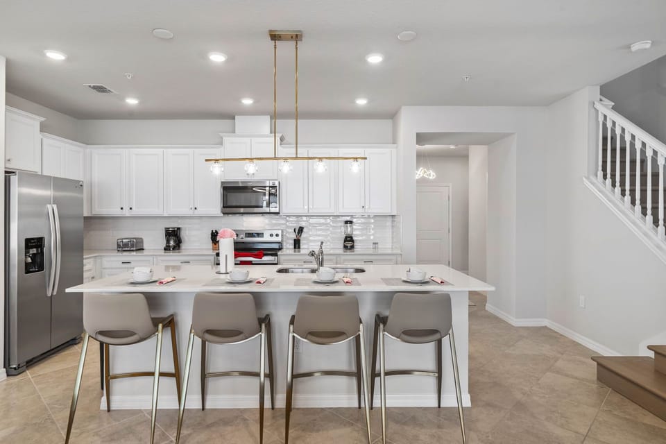 Bright chef's kitchen with a quartz island seating 5, stainless appliances, and chic globe pendants-perfect for breakfasts before the parks!