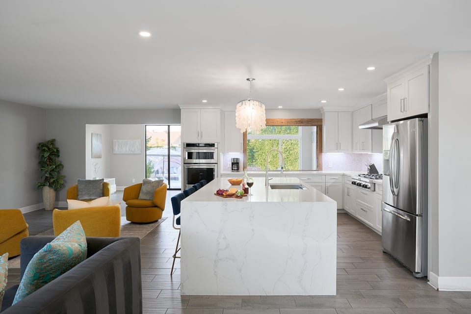 Fully equipped kitchen with stainless steel appliances, a sleek kitchen island with a breakfast bar for casual seating for 4.