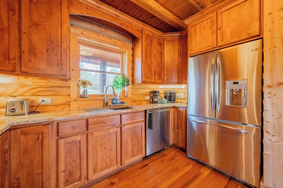 Bright kitchen with window over sink and stainless fridge.