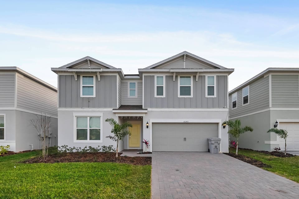 Step into your home away from home with this stylish exterior featuring soft gray siding and crisp white trim. The inviting entry, framed by greenery, leads you to a spacious layout perfect for relaxation after a day of adventure.